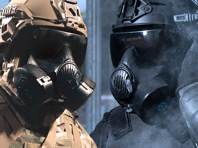 Two individuals wearing tactical helmets and gas masks against a blurred background