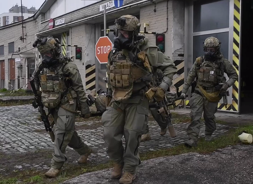 Three soldiers in tactical gear walking on a street with a 'STOP' sign in the background.